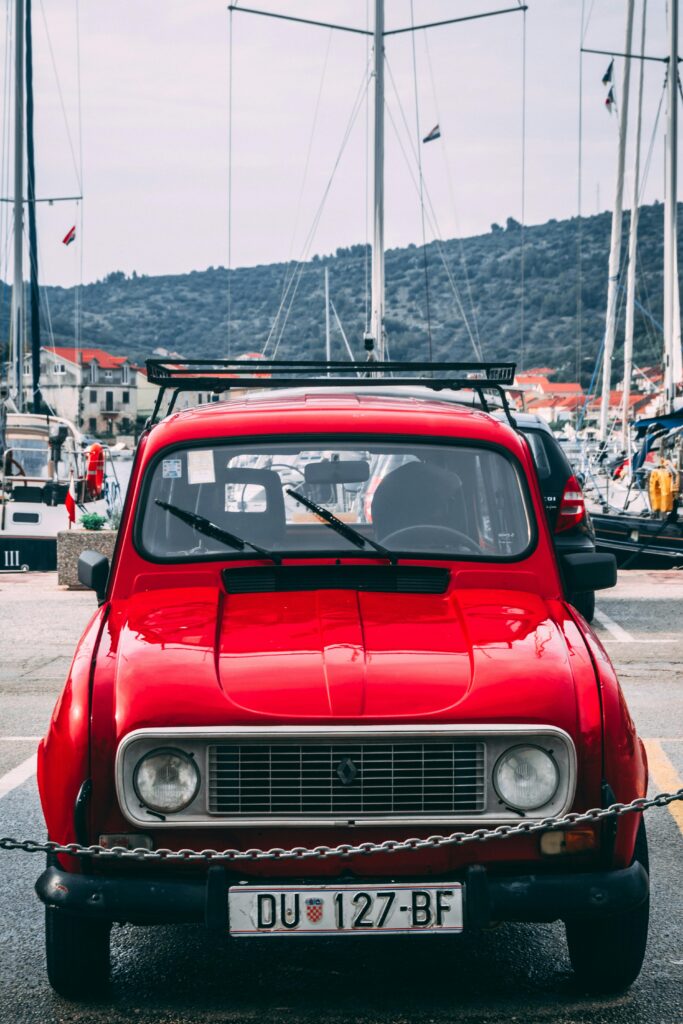 pexels-photo-2290286-2290286 Classic red Renault 4 car parked in Vela Luka, Croatia, with yachts in the background.