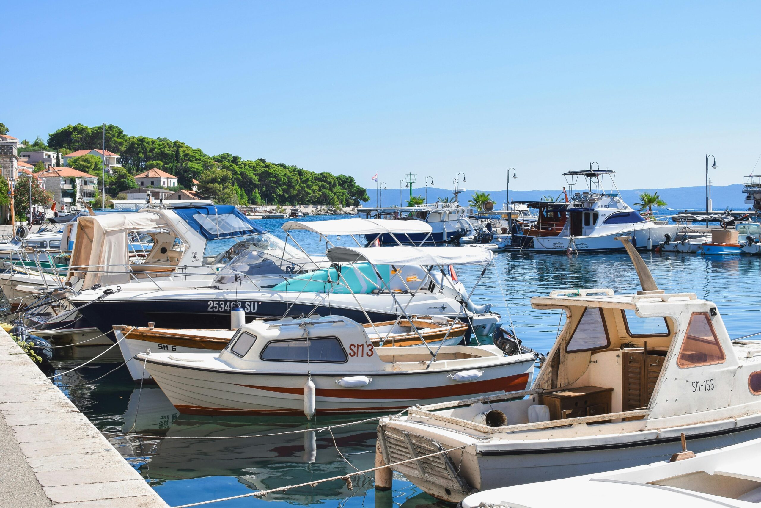 Peaceful scene of boats docked at a harbor in a coastal town on a sunny summer day.